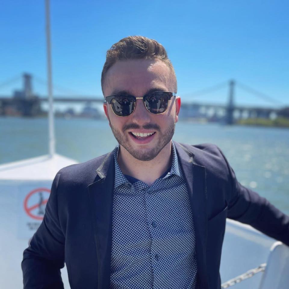 Picture of Zachar Olivan outside on a boat in a suit with sunglasses