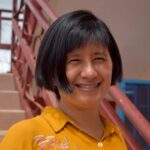 Picture of MIEA Certified Mindfulness teacher Penelope Wong smiling wearing a yellow shirt.